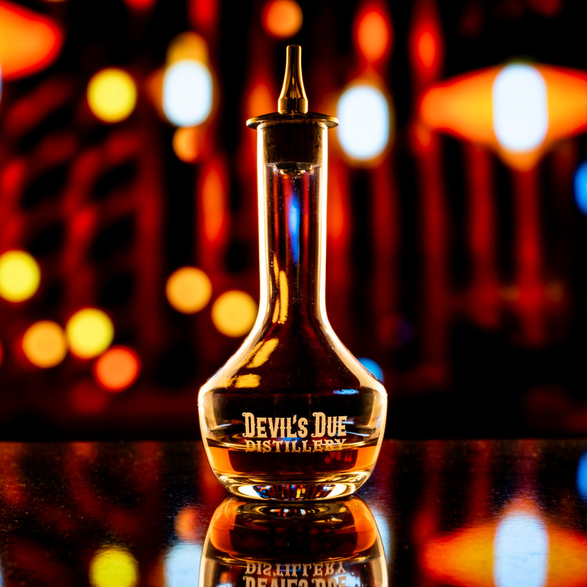 Wholesale engraved 3 oz. Gold Bitters Bottle customized with Devils Due Distilling logo on a bokeh background