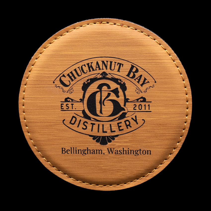 Wholesale engraved Golden Wheat Round Coaster customized with Chuckanut Bay Distillery logo on a black background