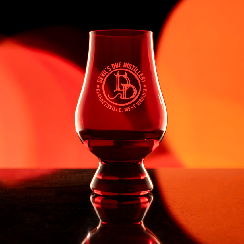 Wholesale engraved Red Glencairn blind tasting glass customized with Devils Due Distillery logo on a bokeh background