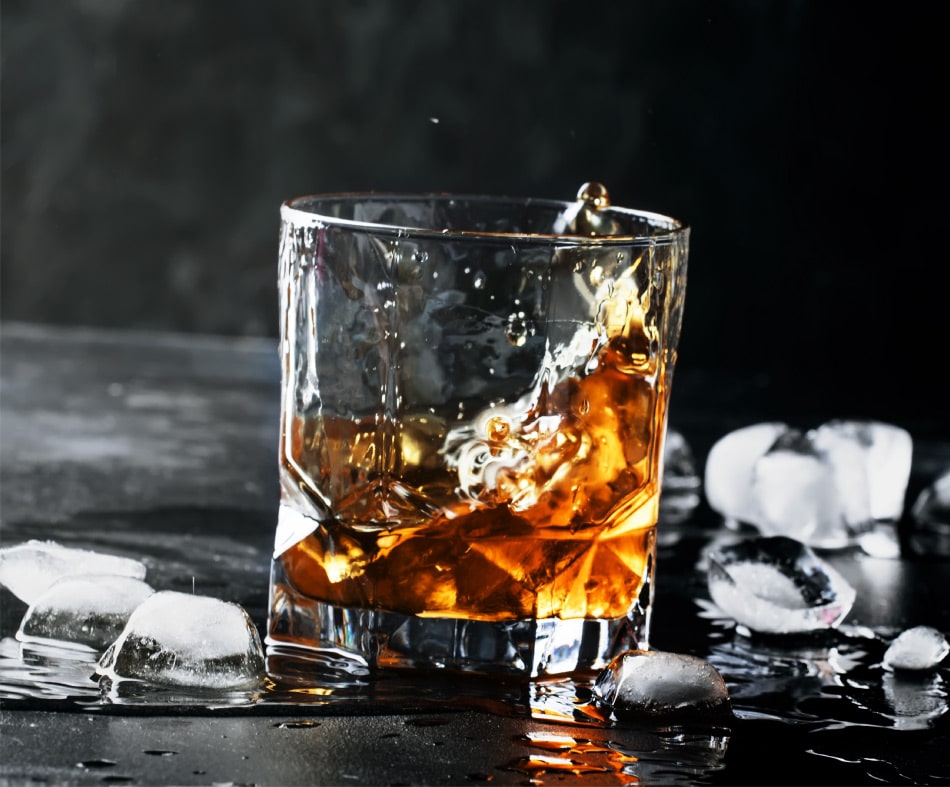 Premium Photo  Pouring whisky from a jigger into a rocks glass with a big  ice cube