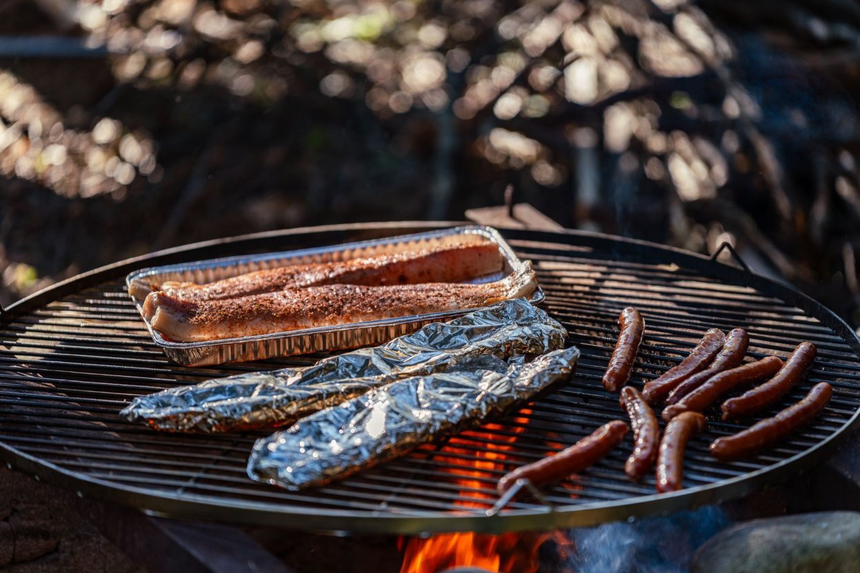 fish and sausages grilling on an outdoor barbecue