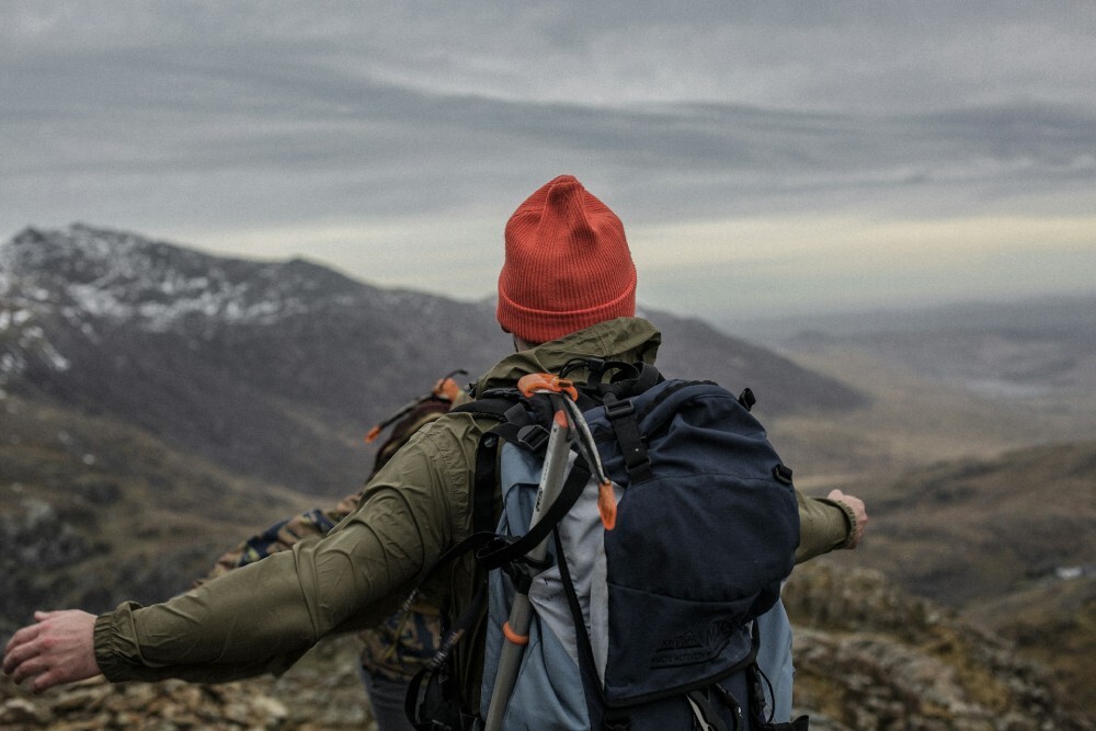 man with backpack standing on cliff