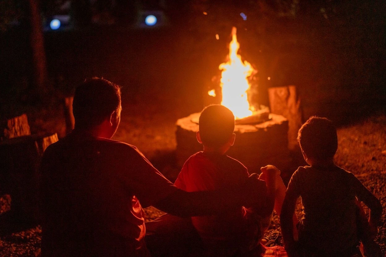 A man and two children sitting by a campfire