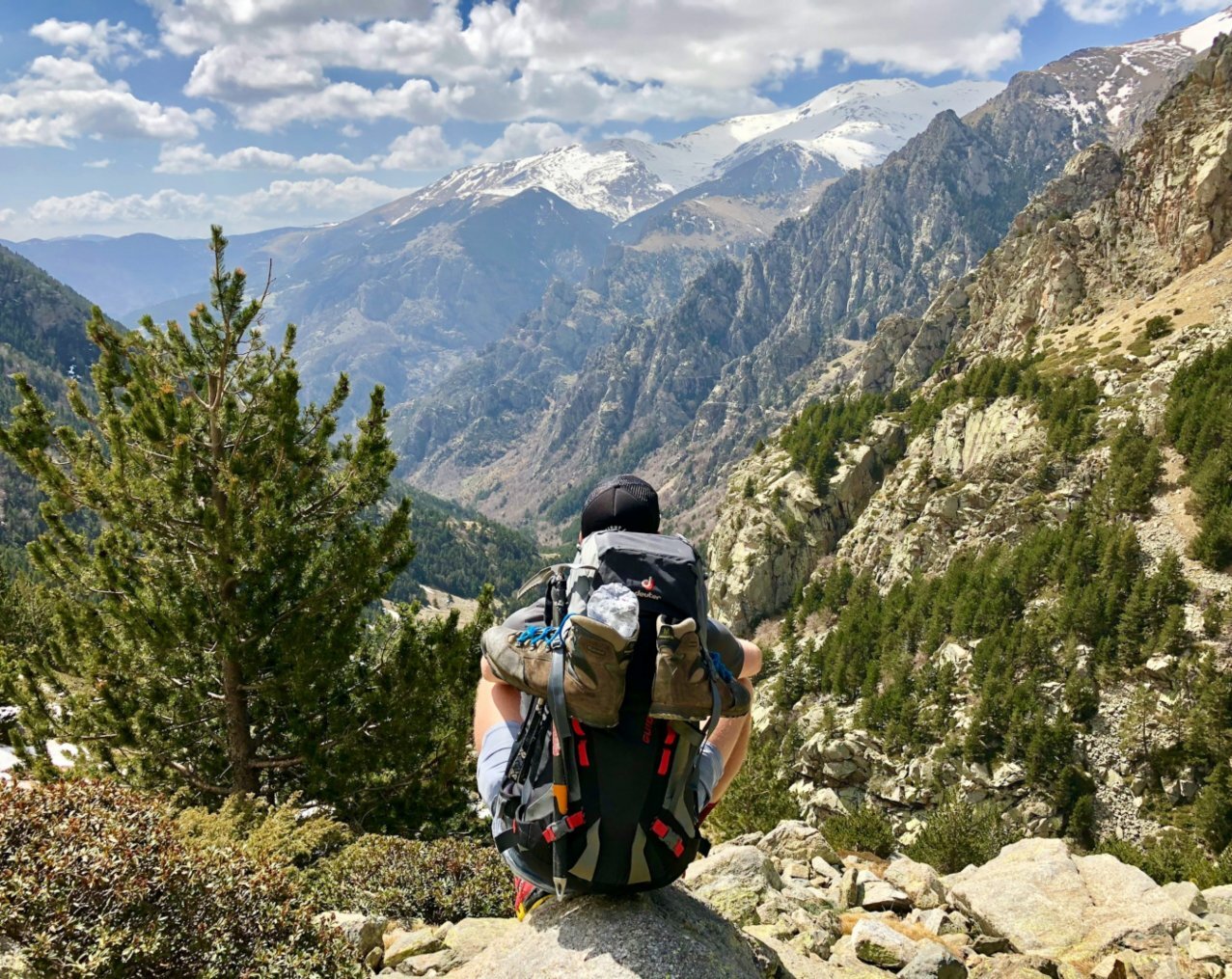 A man sitting on a cliff overlooking mountains