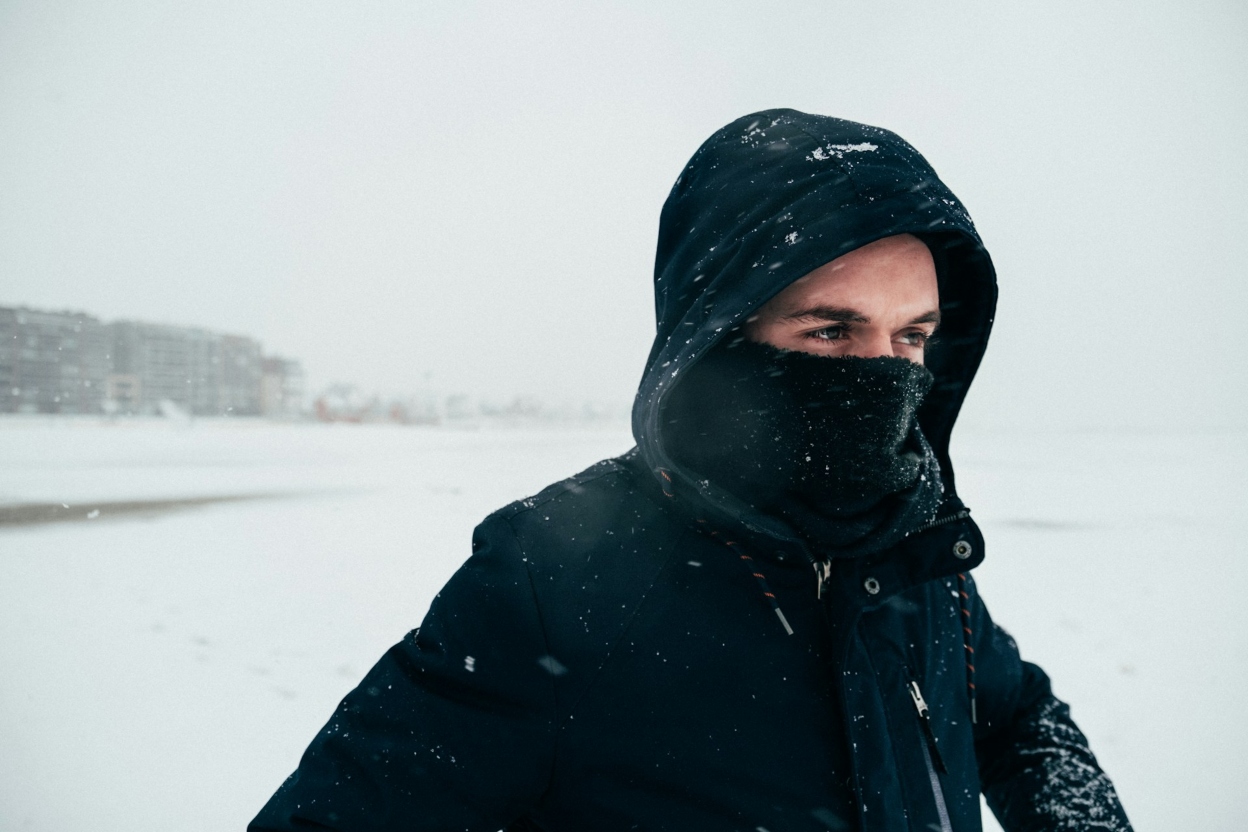 man in the snow in coat and neck gaiter