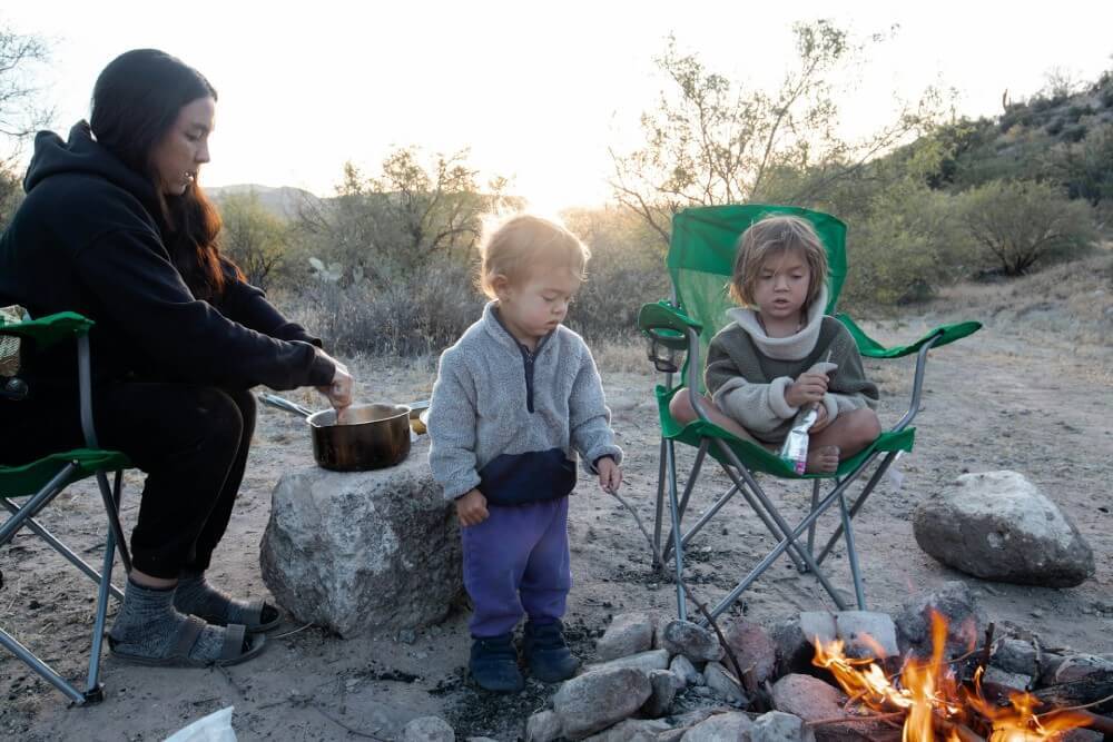 woman and two children sitting by fire pit