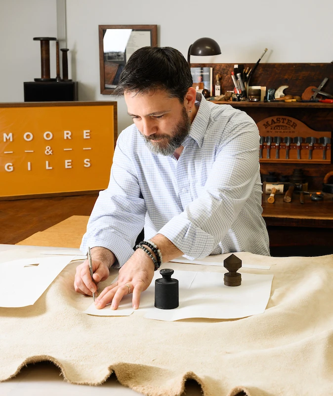 Moore & Giles craftsperson sewing leather in the workshop