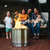 Bonfire being used with stand on a deck, with a family in the back.