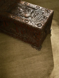 Caliche Silk rug in Moss, styled vignette with a carved wooden chest