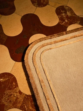 Arc rug in Amber, corner detail on a patterned marble floor