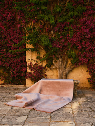 Mohair Sheared rug in Orchid, rolled and shown against garden greenery