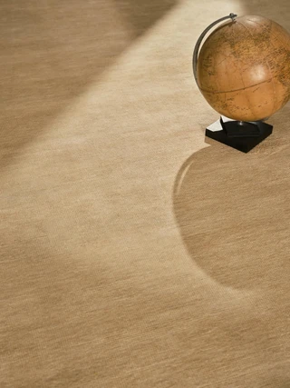 Caliche Silk rug in Dawn, styled vignette with a vintage globe