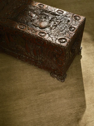Caliche Silk rug in Moss, styled vignette with a carved wooden chest