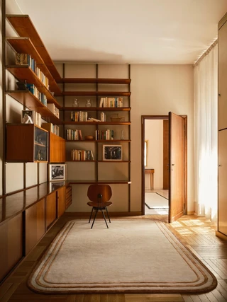 The Rug Company Arc rug, Amber colourway, styled in a wood-paneled library with built-in bookshelves