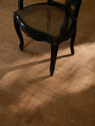 Vara rug in Clay, styled vignette with a cane-back chair