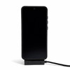 A black phone is displayed on a charger, connected by a charging cable. The charger has a sleek design.