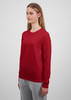 A long sleeve women's tee in red, featuring a simple design and a snug fit. The model is wearing grey pants.