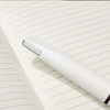 A white pen rests on a lined notebook page, featuring a sleek design and minimalistic style.