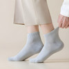 A pair of light grey socks is being pulled up, showcasing a ribbed design. The background is a neutral tone.