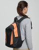 A black and orange backpack is worn on the back of a person, showcasing its stylish design and spacious compartments.