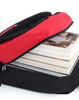 A black and red backpack with a partially opened zipper, revealing several stacked books inside.