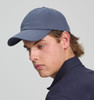 A cotton twill unstructured cap in navy blue, worn by a model with light brown hair. The cap has a logo.