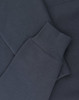 A close-up of a navy oversized hoodie featuring ribbed cuffs and soft fleece material. It includes a logo.
