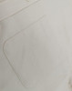 A close-up of a light-coloured cotton blend shirt featuring a back pocket and a button detail.
