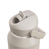 A drink bottle in a light beige colour with a flip straw lid and a side handle. It features a logo on the side.