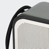 A grey and white portable speaker with a textured surface and a black strap attached.