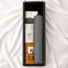 A grey umbrella nestled in a black box alongside snack items, including pretzel balls and popcorn.