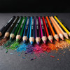 A set of 12 colouring pencils in various vibrant colours, arranged beside shavings of different hues.