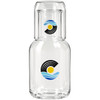 A glass carafe with a matching cup set, featuring blue and yellow wave and sun designs, includes branding.