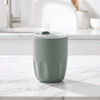 A drink bottle in a soft green hue with a clear lid, featuring a textured body and an internal ceramic liner.