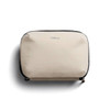 A beige tech kit with a zip closure and a logo on the front, featuring a textured fabric design.
