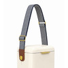 A cooler with a cream body features a navy and white striped shoulder strap and a brown leather accent.