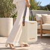 A white cooler bag with striped handles is being carried by a person in light, casual attire.