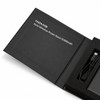 A black wireless power bank with a USB cable, displayed in a sleek box, featuring branding.