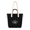 A black tote bag with cream handles and a front pocket, featuring a logo on the front.