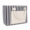 A striped tote bag featuring navy and white stripes with a solid cream front pocket and two handles.