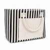A striped tote bag with black and cream colours, featuring a front pocket and two top handles.