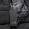 A black unisex puffer vest with a zip and an inner lining featuring a branding logo. A tag is attached.