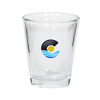 A clear glass shot glass featuring a logo with blue waves and a sun design.