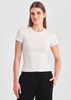 A women's white baby tee with a fitted silhouette, paired with black pants. The model is smiling and standing straight.