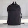 A black backpack with a sleek design and a front pocket, featuring straps and a logo on the side.