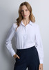 A women's long sleeve shirt in white with a button-up front and a collar, paired with dark pants.