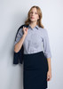 A woman wearing a blue and white check 3/4 sleeve shirt, holding a navy blazer over her shoulder.