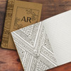 An intricately designed brown notebook featuring a geometric patterned interior with lined pages.
