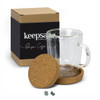 A glass coffee mug with a cork coaster and a box. The mug features a transparent design, showcasing its contents.