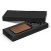 A rectangular wooden key ring in a black packaging box. The key ring is attached to a metal ring.